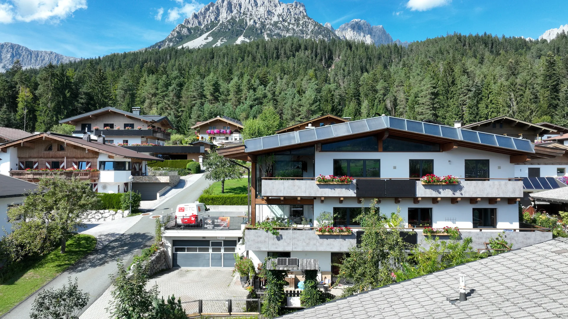 Außenansicht des Apartment FALKENSITZ in Ellmau am Wilden Kaiser — Fassade mit Garagen und Balkon-Geranien